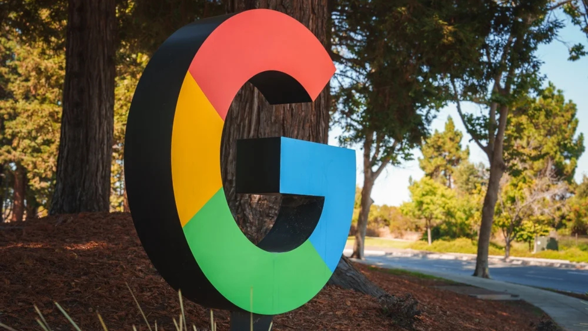 Google logo displayed outside a corporate campus amid trees and landscaping