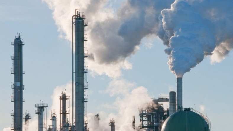 Industrial facility with carbon capture infrastructure and exhaust stacks releasing steam