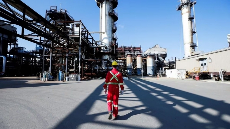Industrial refinery site with worker walking through plant