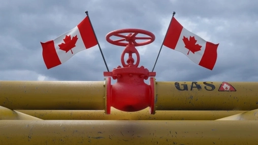 Red industrial pipeline valve with two Canadian flags mounted on yellow gas pipework under a cloudy sky