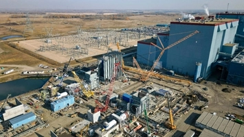 Drone shot of an industrial construction site with cranes, a blue warehouse building, and power substation