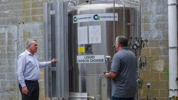 Two engineers inspecting a CarbonQuest liquid carbon dioxide storage tank at an outdoor industrial site