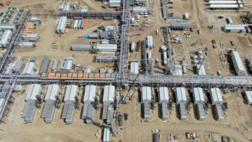 Aerial view of a large gas plant with rows of modular units, pipeline infrastructure and active construction